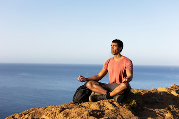 Young man meditating on top ocean cliff.. - Powered by Adobe