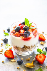 Parfait with cream or yogurt, jam and fresh berries in the glass jar.