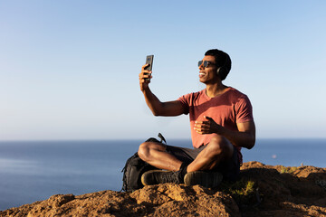 Young man taking selfie photo on a road trip. Man making memories on the mountain.