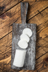 Sliced Soft Goat cheese on a cutting board. Wooden background. Top view