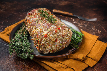 Rolled meat pork roulade with rosemary and thyme. Dark background. Top view