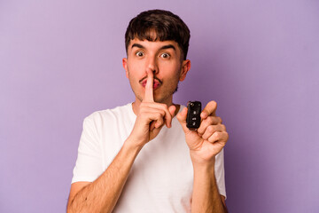 Young hispanic man holding keys car isolated on purple background keeping a secret or asking for silence.