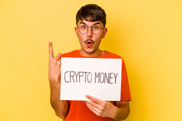 Young hispanic man holding nft placard isolated on yellow background having some great idea, concept of creativity.