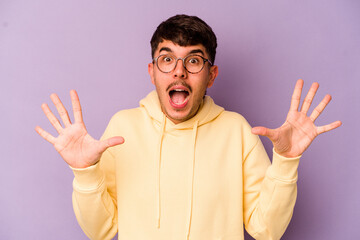 Young caucasian man isolated on purple background receiving a pleasant surprise, excited and...
