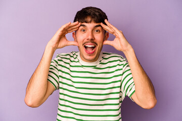 Young caucasian man isolated on purple background receiving a pleasant surprise, excited and raising hands.