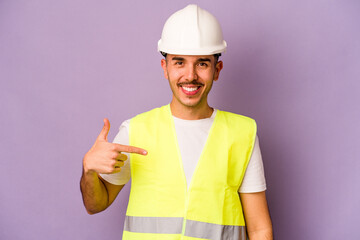 Young hispanic worker man isolated on purple background person pointing by hand to a shirt copy space, proud and confident