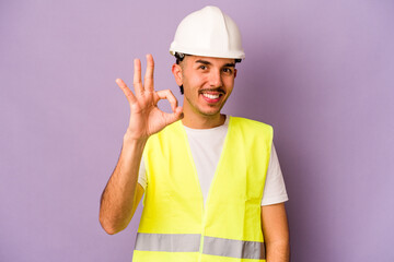 Young hispanic worker man isolated on purple background cheerful and confident showing ok gesture.