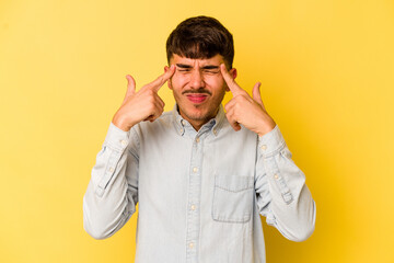 Young caucasian man isolated on yellow background focused on a task, keeping forefingers pointing head.