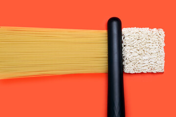 Spaghetti curlers and wavy instant noodles on orange background. The concept of straightening or...