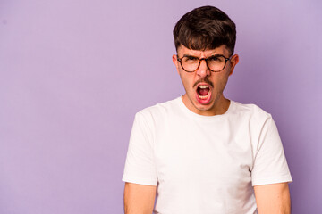 Obraz premium Young caucasian man isolated on purple background shouting very angry, rage concept, frustrated.