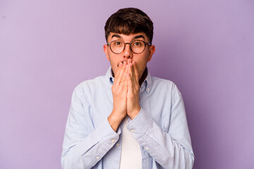 Young caucasian man isolated on purple background shocked, covering mouth with hands, anxious to discover something new.