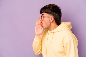 Young caucasian man isolated on purple background is saying a secret hot braking news and looking...