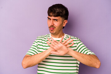 Young caucasian man isolated on purple background doing a denial gesture