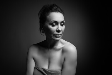 Portrait of a sensual fifty -year -old woman on grey studio background. Monochrome shot.