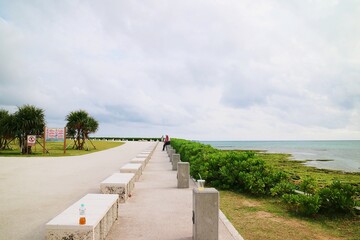 Seaside park with rows of stone seats and pillars along the sandy beach and emerald green grass