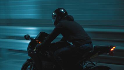 A man rides a sports motorcycle through the city at night
