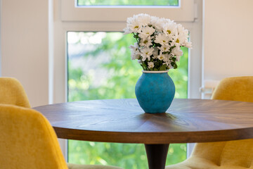 Round table with flowers in vase and yellow chairs around