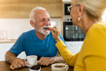 Senior couple drinking coffee and eating chocolate at home