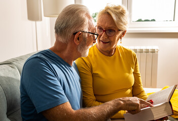 Senior couple reading book at home