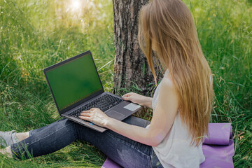 girl sits on the grass and works at a laptop. freelance. selfeducation. the concept of distance learning outdoors.