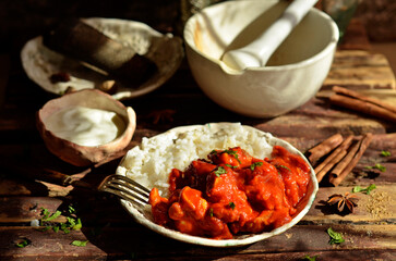 Chicken tikka masala with rice on a plate on a dark wooden background