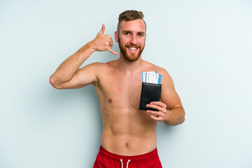 Fototapeta premium Young caucasian man holding a passport isolated on blue background showing a mobile phone call gesture with fingers.