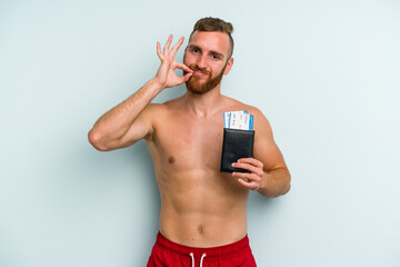 Young caucasian man holding a passport isolated on blue background with fingers on lips keeping a secret.