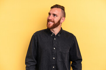 Fototapeta premium Young caucasian man isolated on yellow background relaxed and happy laughing, neck stretched showing teeth.