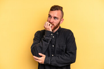 Fototapeta premium Young caucasian man isolated on yellow background biting fingernails, nervous and very anxious.