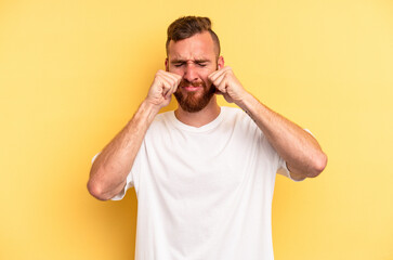 Young caucasian man isolated on yellow background whining and crying disconsolately.