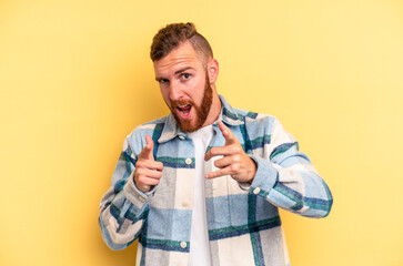 Young caucasian man isolated on yellow background pointing to front with fingers.