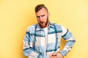 Young caucasian man isolated on yellow background having a liver pain, stomach ache.