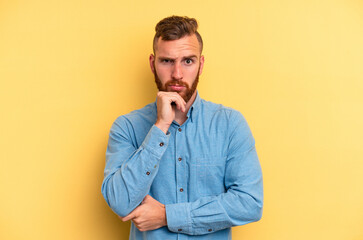 Young caucasian man isolated on yellow background thinking and looking up, being reflective, contemplating, having a fantasy.