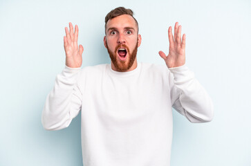 Young caucasian man isolated on blue background celebrating a victory or success, he is surprised and shocked.