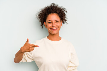 Young Brazilian woman isolated on blue background person pointing by hand to a shirt copy space, proud and confident