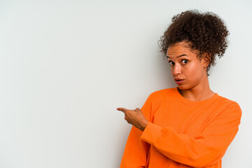 Young Brazilian woman isolated on blue background smiling and pointing aside, showing something at blank space.