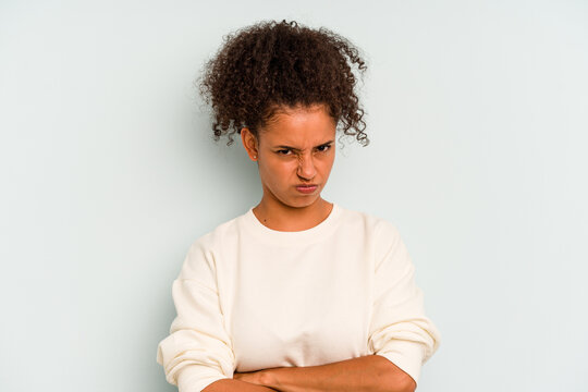 Young Brazilian woman isolated on blue background frowning face in displeasure, keeps arms folded.
