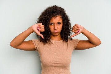 Young Brazilian woman isolated on blue background showing a dislike gesture, thumbs down. Disagreement concept.