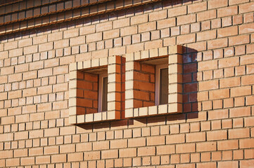 Two small square windows in the wall of a red brick building. Texture of salt on the surface.