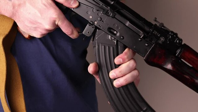 Man detaches ak-47 magazine with cartridges and unloads Kalashnikov assault rifle