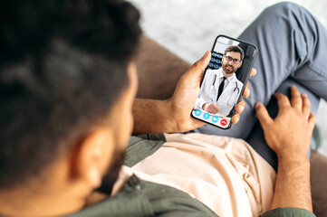 Remote medical consultation. On the phone screen, a Caucasian professional doctor of general...