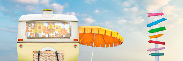 Retro caravan with beach umbrella and colorful wooden direction sign post