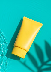 Sun cream yellow tube on the blue water surface with palm leaves shadows. Summer vacation cosmetics...