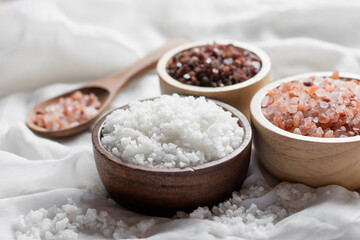 Different types of rice grains put in a wooden cup placed on a white cloth, concept of food and health.