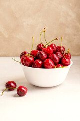 Fresh red cherries in white bowl, on neutral background. Summer delicious fruit.