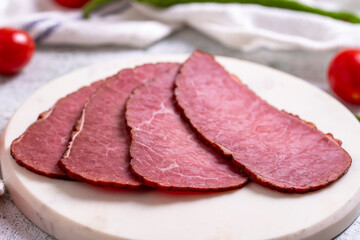 Beef jerky pieces. Sliced pieces of dry meat on a stone floor. close up