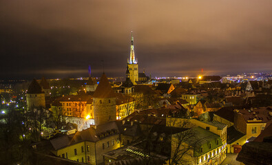 Town illuminated in evening twilight and St. Olaf Baptist Church, sea and port in Tallinn, Estonia	