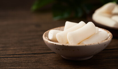 Tteok or Korean Rice Cakes in a dish on a wood background                                                              