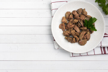 Fried or baked chicken liver with onion and sauce, green parsley leaves on a plate. Meat dish enriched with iron. copy space