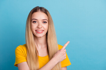 Photo of sweet young woman dressed shirt smiling pointing back finger empty space isolated blue color background